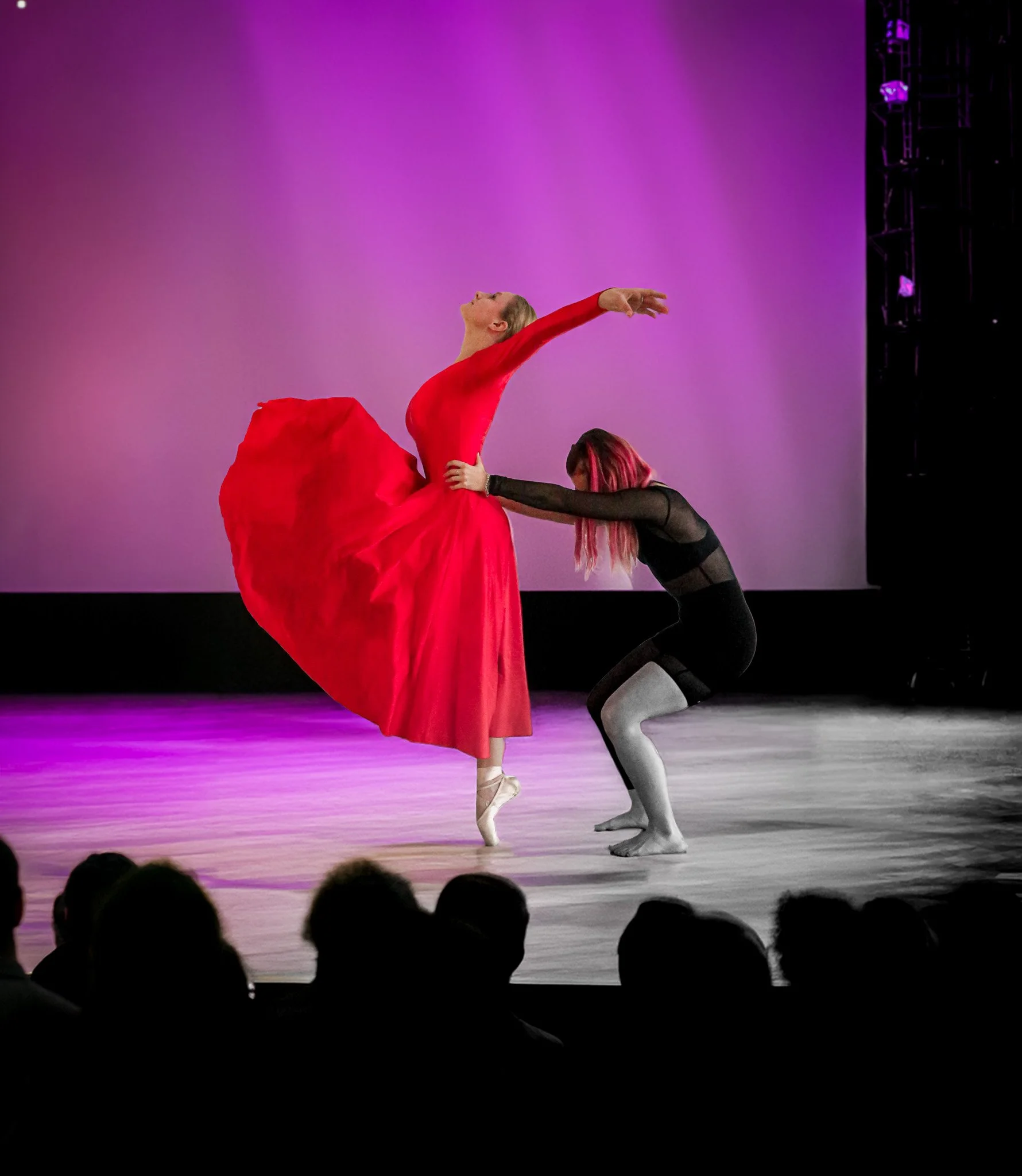 Zwei Tänzerinnen auf der Bühne – eine in leuchtend rotem Kleid auf Spitze, eine in Schwarz – aus der Show »Die gestohlenen Farben«, Step by Step München.